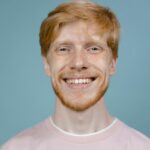 About Portrait of a happy redhead man smiling against a blue background in a studio shoot.